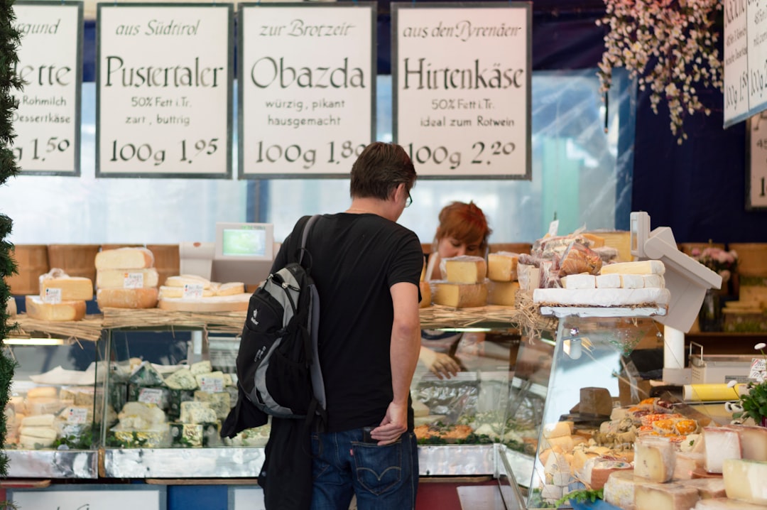 man in black polo shirt standing in front of food counter