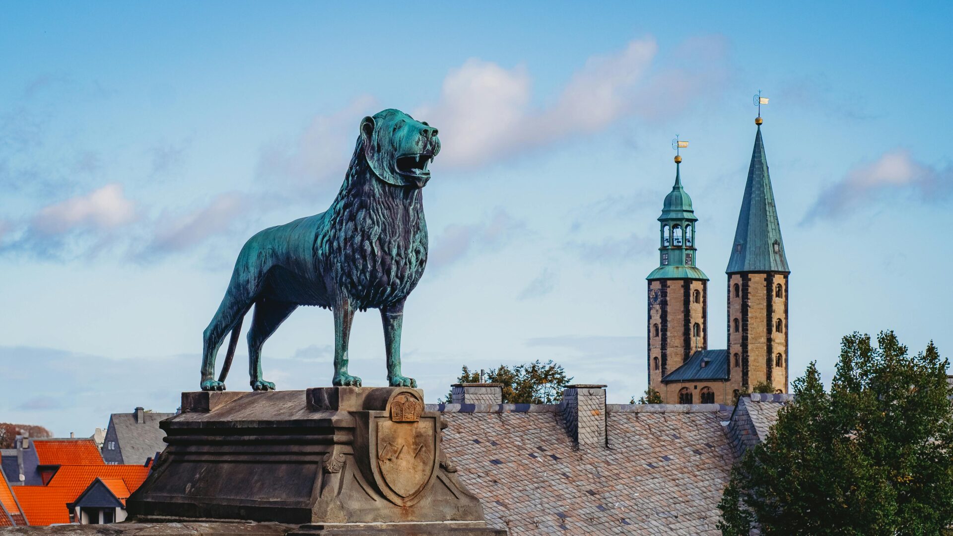 View of the historic Brunswick Lion statue with a church tower in the background on a sunny day.